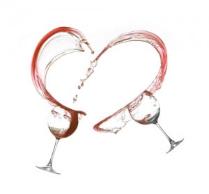 Two glasses splashing red wine into a heart shape on a white background