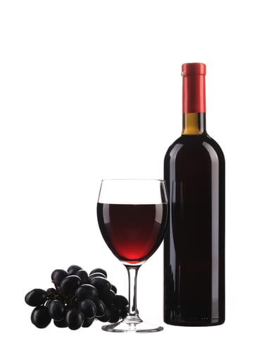 Grapes and a glass and bottle of red wine on a white background